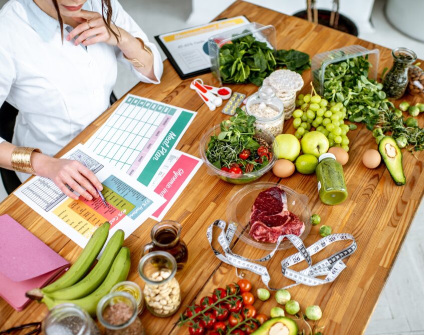 Writing a diet plan on the table full of healthy food